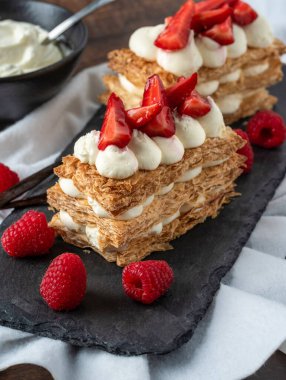  Çilek, ahududu ve kremalı Mille Feuille tatlısı siyah taş tabakta.