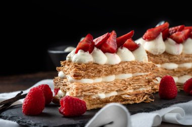  Çilek, ahududu ve kremalı Mille Feuille tatlısı siyah taş tabakta.