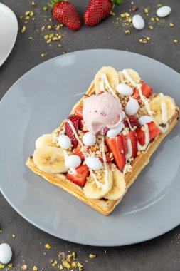 Çilekli ve muzlu Belçika waffleları ve bir fincan kahve.