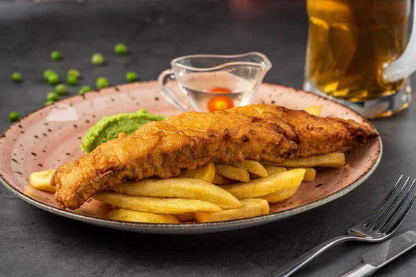 British Traditional Fish and chips with mashed peas, pea sauce and cold beer.