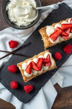  Çilek, ahududu ve kremalı Mille Feuille tatlısı siyah taş tabakta.