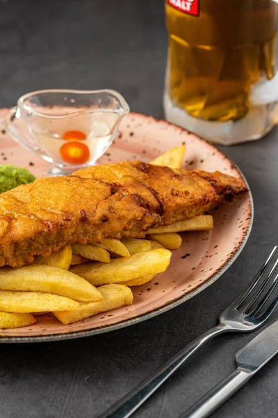 British Traditional Fish and chips with mashed peas, pea sauce and cold beer.