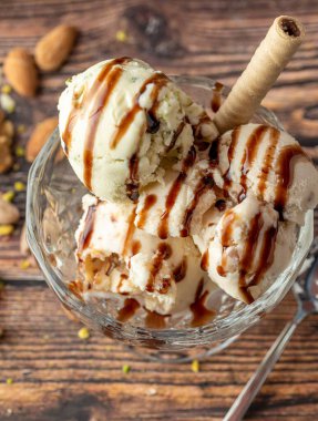 Badem, fıstık ve cevizli Roma dondurması üzerine karamel sosu dökülmüş cam bir kasede..