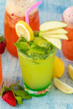 Limonlu ferahlatıcı limonata, mavi arka planda çilek ve nane.