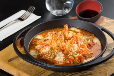 Siyah taş bir tavada domates ve biberli karides güveci..