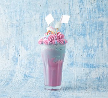 Mavi ve pembe milkshake, mavi arka planda şekerleme ile süslenmiş..