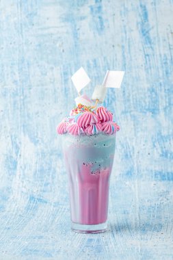 Mavi ve pembe milkshake, mavi arka planda şekerleme ile süslenmiş..