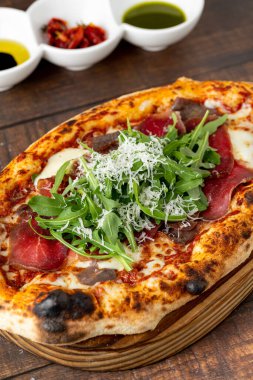 Napoli pizzası, domuz pastırması, roka ve parmesan.