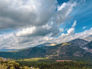 Wide valley view under cloudy sky with mountain ridges and forests