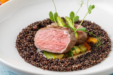 Medium rare beef steak with asparagus and vegetables on quinoa