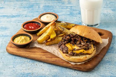 Çedar peynirli ve karamelli soğanlı ezme burger, patates kızartmasıyla servis edilir.