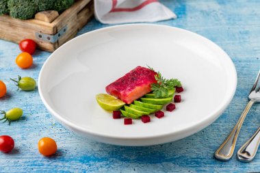 Avokado dilimleri, limon ve pancar ile taze somon filetosu.