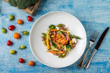 Kurutulmuş somon filetosu, tahıl ve mevsimlik sebzelerle servis edilir.