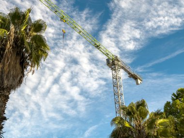 Construction crane arm close-up under bright blue cloudy sky