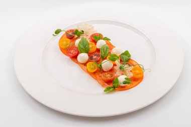 Fesleğen ve otlarla süslenmiş domates ve mozzarella düzenleme.