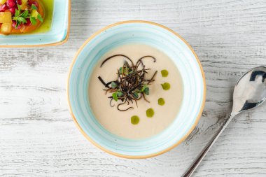 Mavi çerçeveli kapta garnitürlü kremalı balık çorbası.