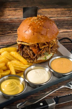 Kızartma ve sosla servis edilen yavaş pişirilmiş biftek burgeri.