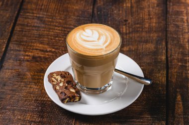 Ahşap masada servis edilen, yapraklı latte ile latte.