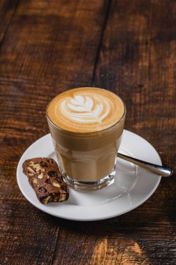 Ahşap masada servis edilen, yapraklı latte ile latte.