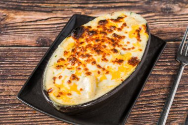 Kırsal ahşap masada servis edilen fırın peynirli patatesler.