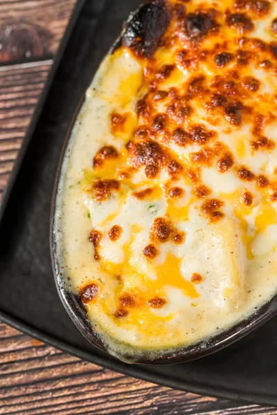 Kırsal ahşap masada servis edilen fırın peynirli patatesler.