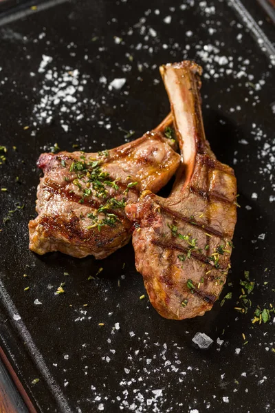 Siyah taş tabakta servis edilen ızgara kuzu pirzolası.