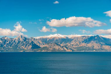 Akdeniz, açık mavi gökyüzü altında karlı Taurus Dağları