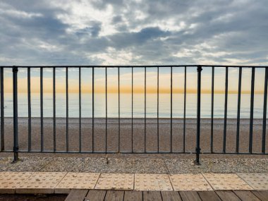 Metal çitli deniz manzarası, sakin deniz ve bulutlu gökyüzü