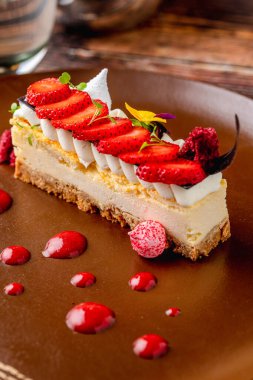Artistik sos sunumlu çilekli cheesecake dilimi.