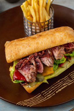 Roast beef sandwich served with fries on rustic plate