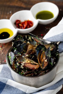 İtalyan midyeleri siyah kasede otlar ve sosla pişirilir.