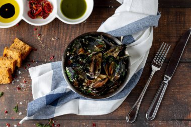 İtalyan midyeleri siyah kasede otlar ve sosla pişirilir.