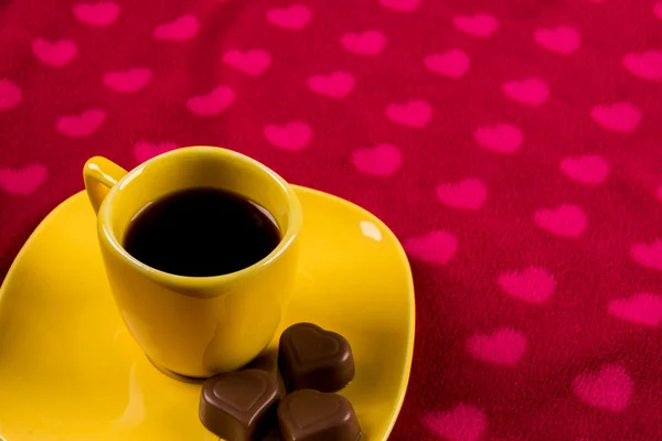 Tasse Kaffee und Schokolade auf herzförmigem Hintergrund — Stockfoto