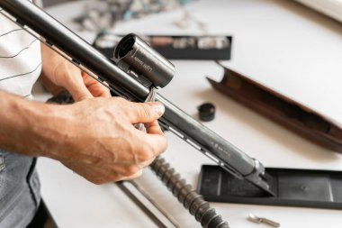 Adamın elleri klasik av tüfeği ve av tüfeğini parçalara ayırıyor.