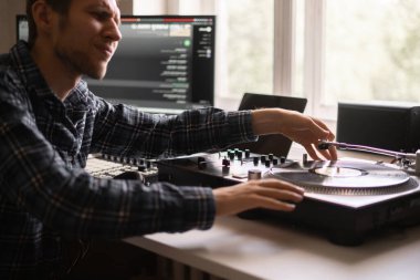 Genç bir erkek ses mühendisi stüdyoda yeni bir müzik projesi üzerinde çalışıyor.