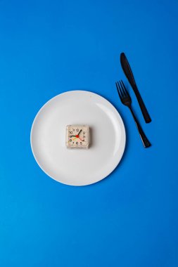 Beyaz tabakta, çatalda ve bıçakta basit bir kavram. Renkli masada yatıyordu. Beslenme zamanı, aşırı kilolu olmayı bırak.