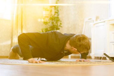 Genç adam evde online spor yapıyor, sağlıklı ve formda kalıyor, mobil cihaz kullanıyor.