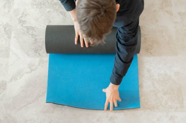 Yoga dersinde yoga minderini yere deviren adam.