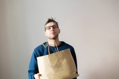 Elinde kese kağıdı olan genç bir adam ürünü teslim edecek.