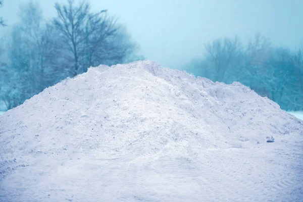 a large pile of snow in the street near road, winter season