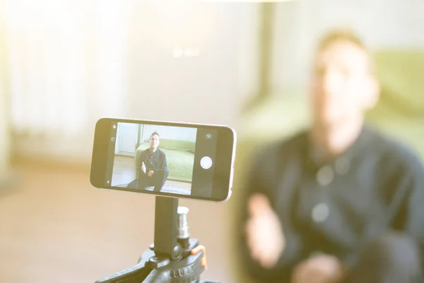 A young man using a phone and chatting on a video call online — Stock Photo, Image