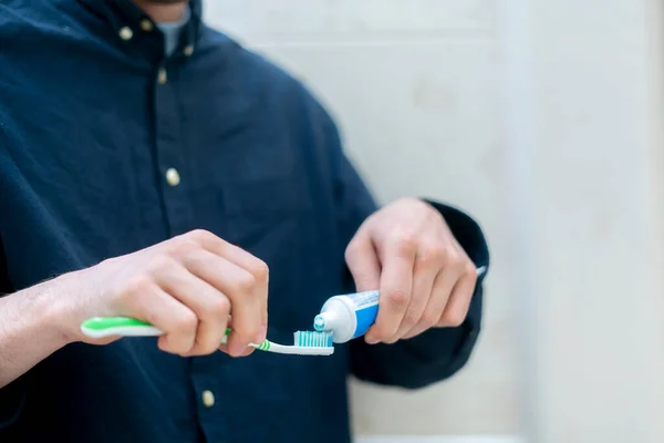 Uma pessoa espremer pasta de dentes em uma escova de dentes no banheiro — Fotografia de Stock