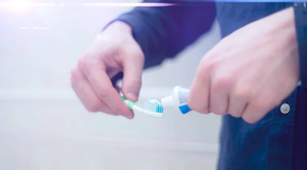 Egy személy fogkrémet présel egy fogkefére a fürdőszobában — Stock Fotó
