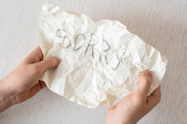 Una persona mani che tengono un foglio di carta con la parola dispiaciuta — Foto Stock