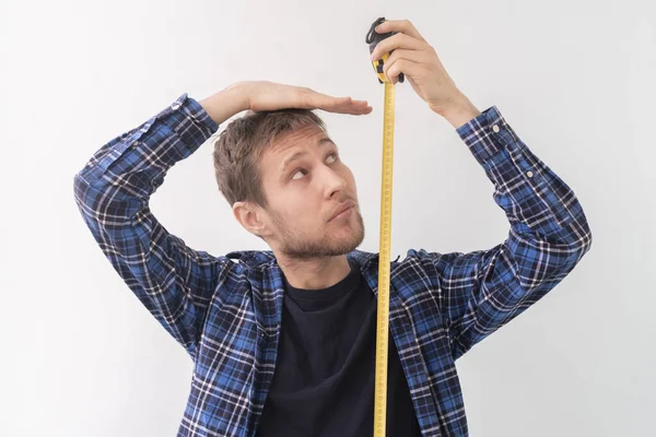 Un adolescent adulte simple homme avec un ruban à roulettes mesurer la hauteur contre le mur — Photo