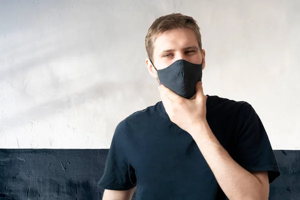Молодий чоловік носить чорну текстильну маску, щоб захистити від вірусу ковадла-19, одягу повсякденного способу життя — стокове фото