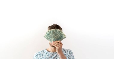 Genç bir erkek, elinde bir paket nakit para tutuyor ve yüzü örtüyor, başarı kazanma kavramı.