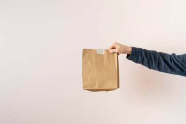 Bir el tutuşu. Eve yiyecek getiren bir kağıt paket.