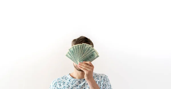 Un jeune homme tenant un paquet de monnaie fiduciaire dollar et couvrir le visage, concept de gain de succès — Photo