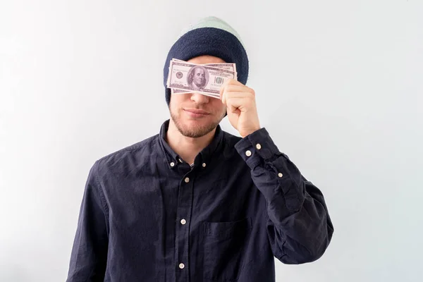 Mladý muž držící balíček dolarové hotovosti a zakrýt tvář, koncept úspěchu vydělávat — Stock fotografie
